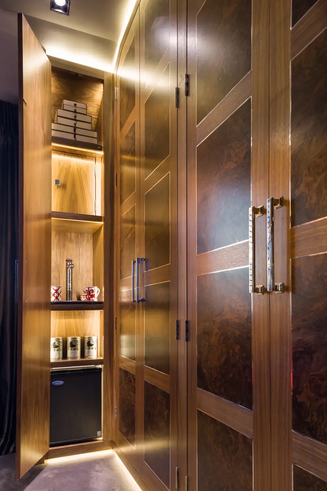 Burr walnut wardrobe doors opened on lit shelves, made by Cochrane Bespoke, in a Chelsea home in London